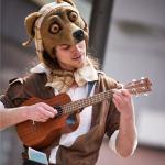 An image of an actor dressed as an animal playing a ukulele