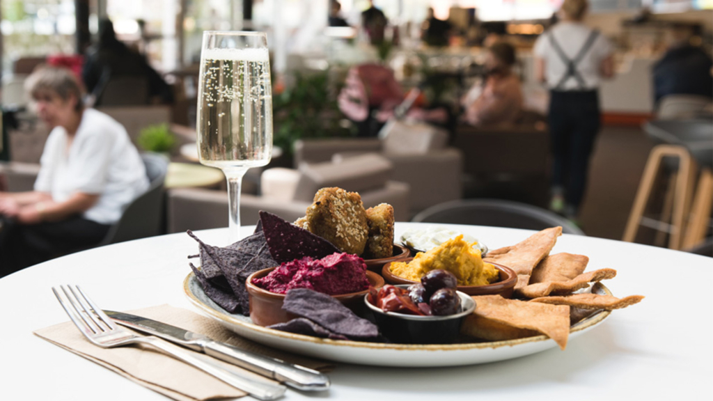 A plate full of food in the cafe bar alongside a glass flute of bubbly champagne.