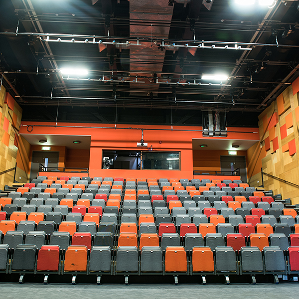The auditorium featuring many rows of fold-up chairs in the theatre.