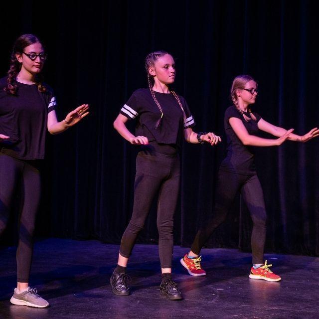 A group of children doing Street Dance whilst stood on a stage.