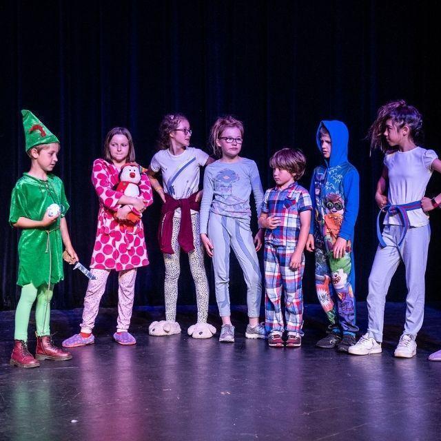 A group of children rehearsing a performance on stage.
