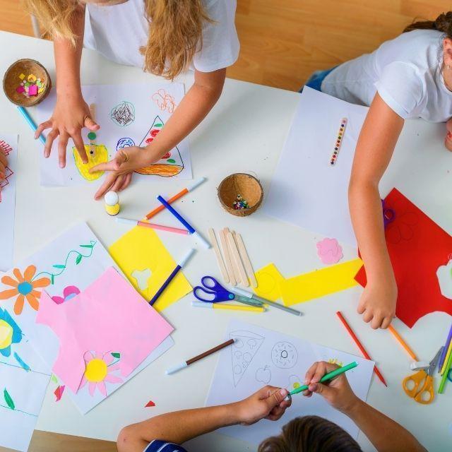 A group of children doing arts and crafts at a table.