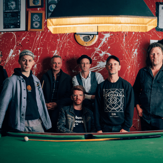 An image of the Peatbog Faeries stood behind a snooker table.