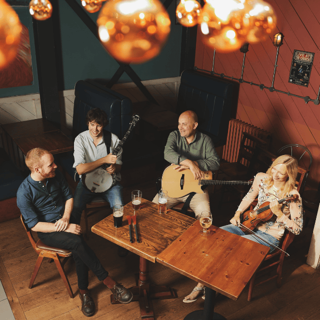 Urban Folk Quartet sat around a table with instruments on their laps