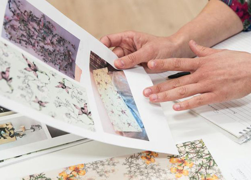 Someone holding a piece of paper that has different floral prints on it.