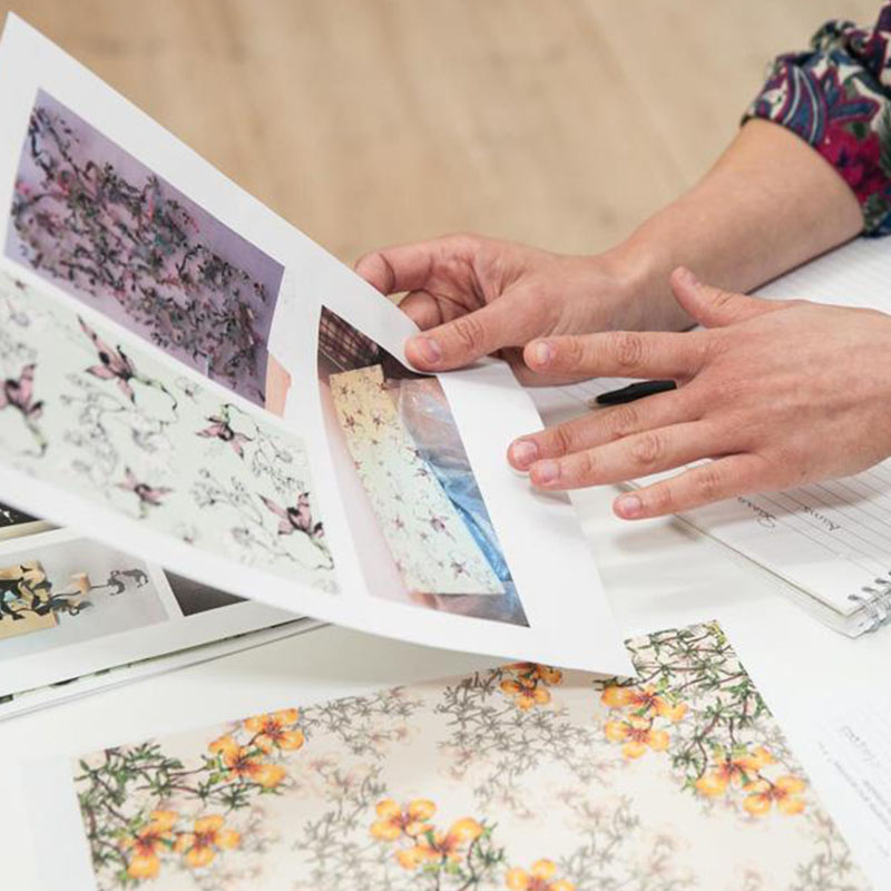 Someone holding a piece of paper that has different floral prints on it.