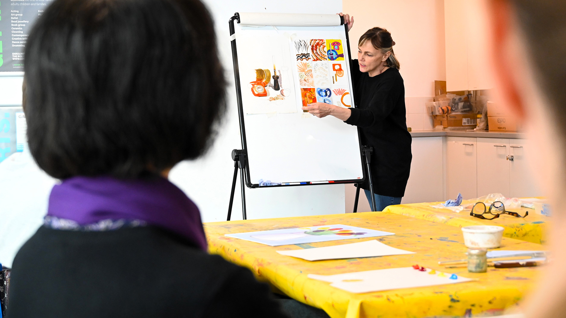 Someone holding different art prints on a whiteboard.
