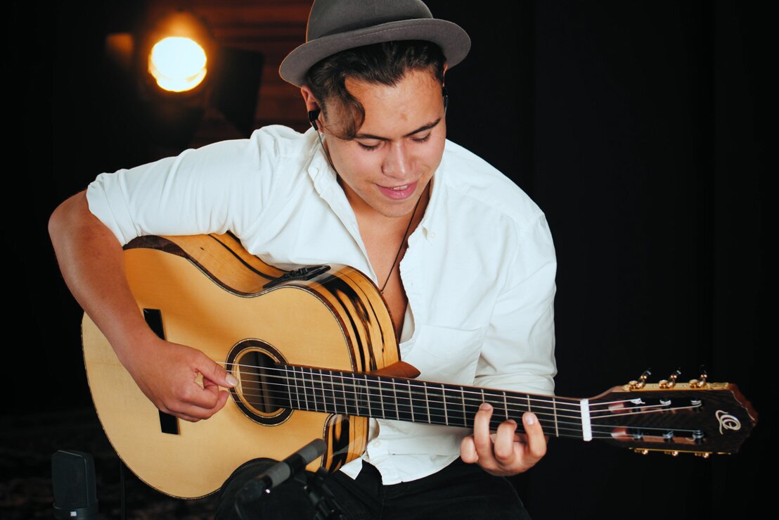 Billy Watman plays his guitar whilst smiling