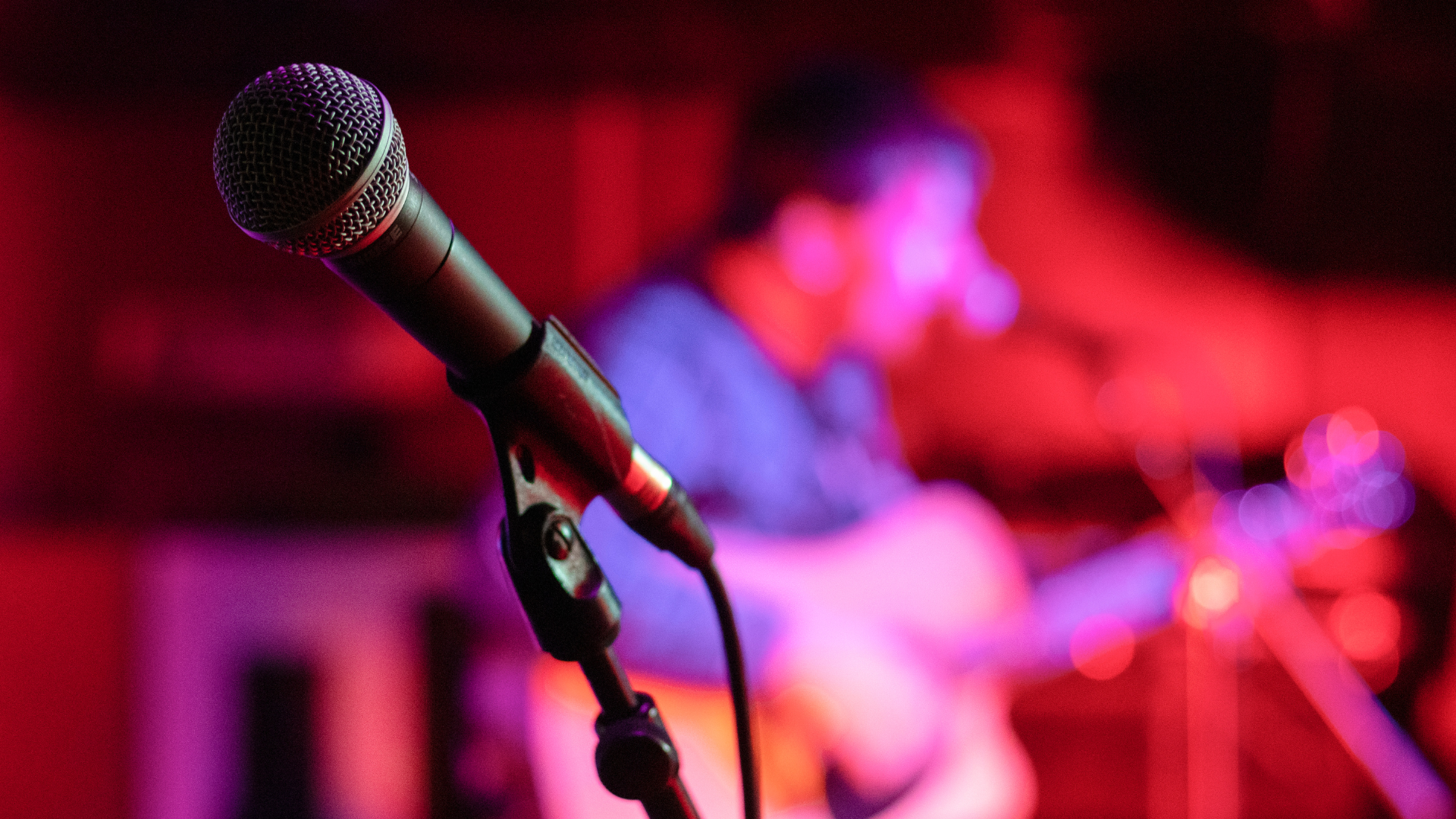 A microphone is pictured on stage with lighting spotlighting it.