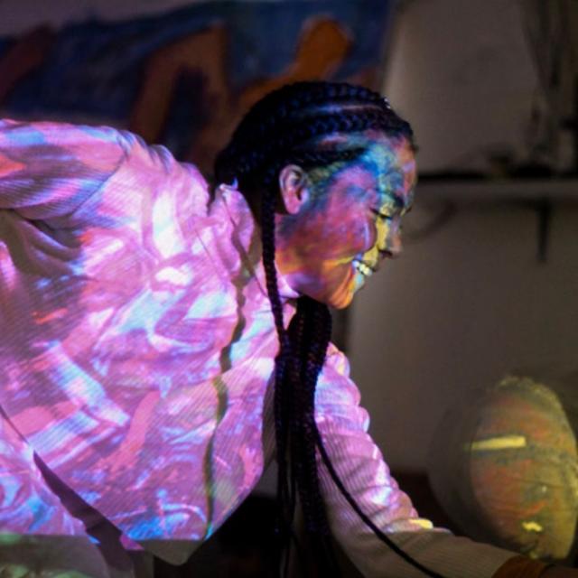 Child smiling, lit up with multi-coloured light installation