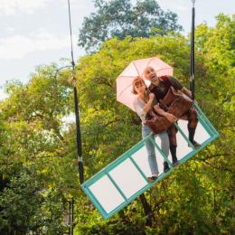 an image of the characters Daisy and Ian sitting on a suspended luggage rack